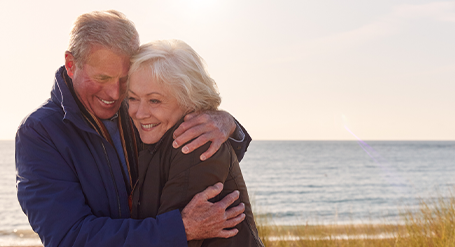 Older Couple hugging By The Beach